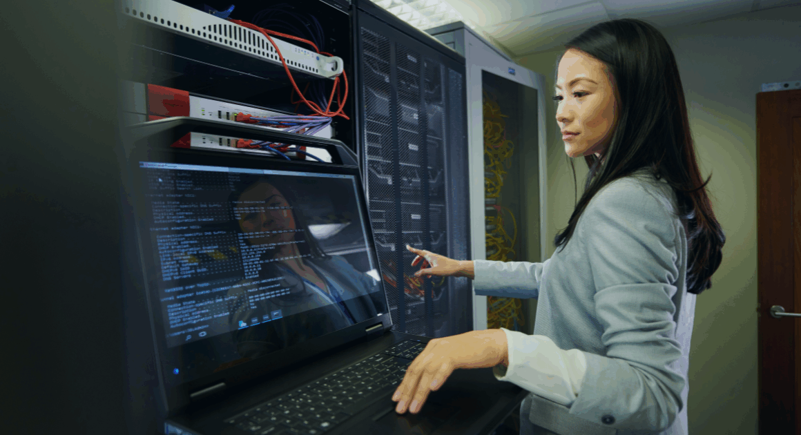 Engineer operating computer hardware while analyzing data on a connected monitor.