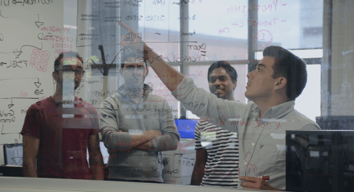 OPAL-RT engineers discussing real-time power system models at a whiteboard filled with electrical calculations.